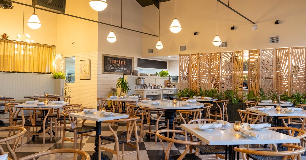 A cozy interior with tables, wooden chairs, pendant lights and a decorative wooden partition