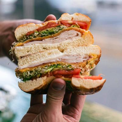 A person holding a bagel sandwich, hand shot.