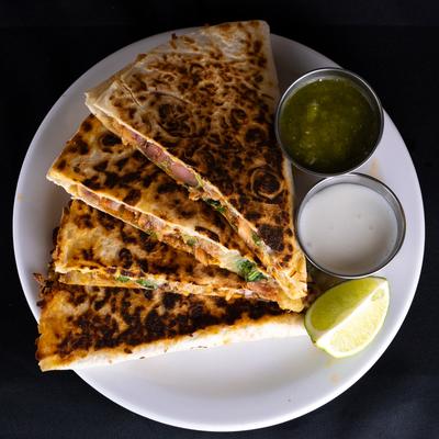 Quesadilla served with green salsa, crema and a lime wedge.