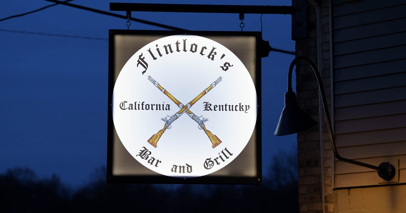 Exterior, a shot of a hanging logo sign at Flintlock's in the evening