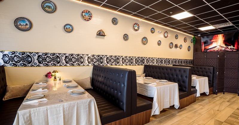 Modern interior dining area with dining booths along wall set for guests
