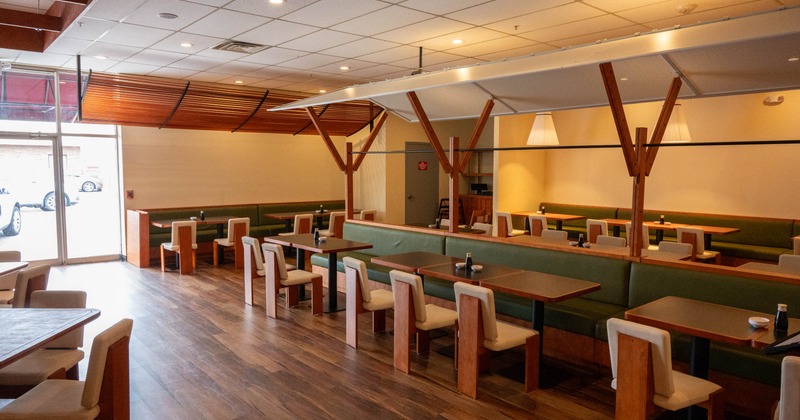 Interior, wooden tables, green cushioned booths, and modern light fixtures