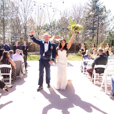 Bride and groom cheerfully walk down the aisle after their outdoor wedding ceremony.