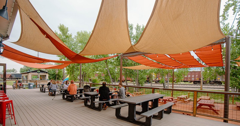 Patio, conjoined tables and benches, covered with sun shade sails