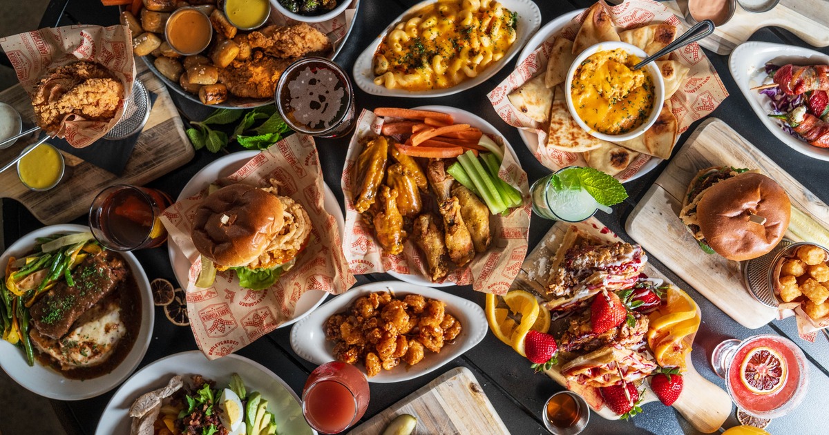 Various dishes served on the table alongside cocktails and beer