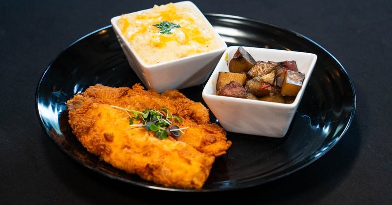 Fried fish wit sides of fried potatoes and mac and cheese