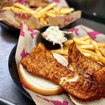 A fish sandwich served with french fries and coleslaw.