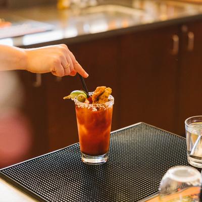 Bartender garnishing a Bloody Mary cocktail.