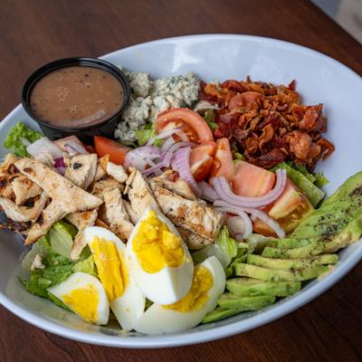 Cobb salad served with a cup of dressing.
