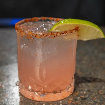 A glass of Watermelon refresher, garnished with a spiced rim and a lime wedge.