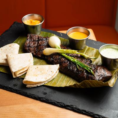 Grilled skirt steak, with onions, tortillas, and dipping sauces.