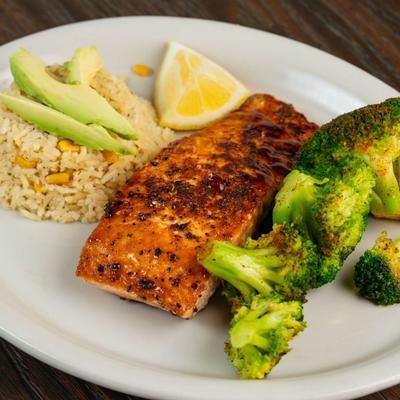 Norwegen salmon with sides of broccoli and rice topped with avocado slices.