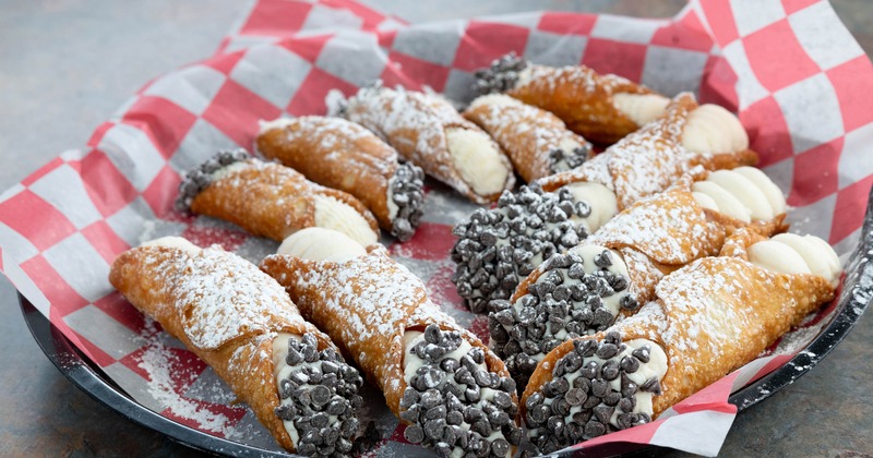 Cannoli garnished with powdered sugar and chocolate chips