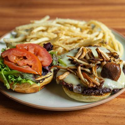 An open-faced burger topped with cheese and mushrooms, a bun with lettuce and tomato