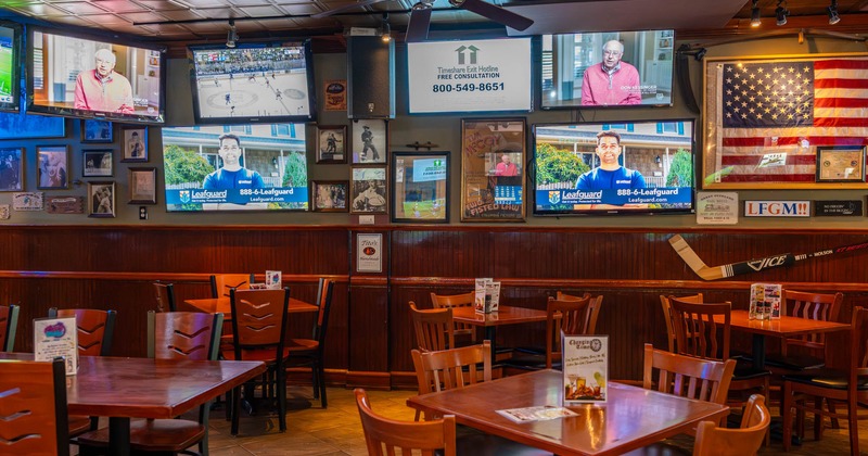 Interior, seating area with tables and chairs, TVs on the wall