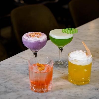 Four colorful cocktails sitting on a marble counter.