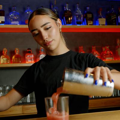 Person pouring a drink behind the bar.