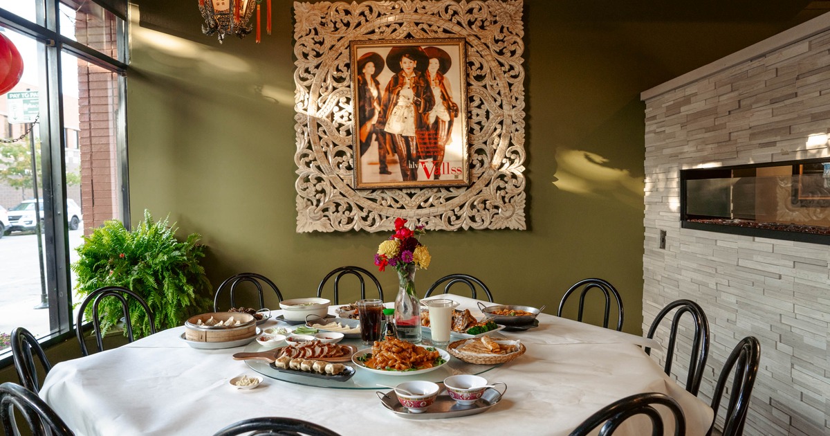 Round dining table with assorted dishes, surrounded by black chairs, in an ornate decorated room