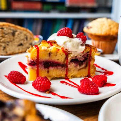 Rasberry Cake topped with whipped cream, fresh raspberries and drizzle of sauce.