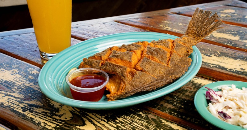 Crispy Scored Flounder on a blue plate with a cup of red sauce