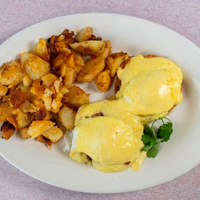 Eggs Benedict served with home fries on the side.