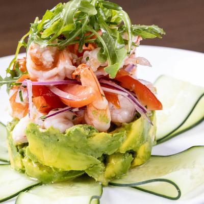 Shrimp and Avocado Salad topped with arugula, garnished with cucumber slices.