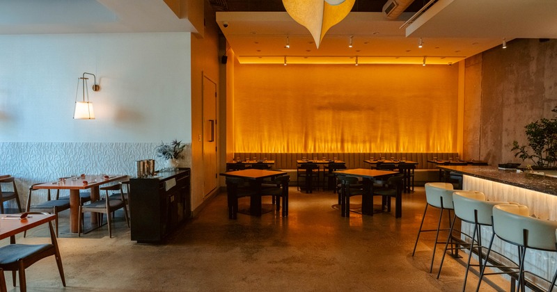 Interior seating area with warm lighting, wooden tables and a bar