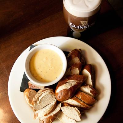 Giant pretzel served with ale and cheddar dip, accompanied with a glass of beer.