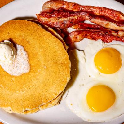 Pancakes with butter, sunny side up eggs, and bacon.