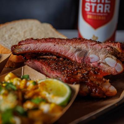 Pork ribs with sides, bread, and beer, close up.