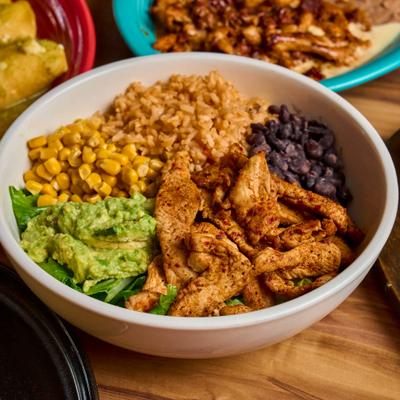 Chicken bowl with black beans, rice, guacamole, and greens.