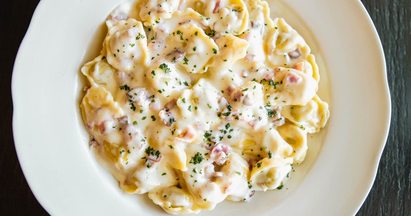 Veal and pork tortellini with prosciutto in a white cream sauce, top view