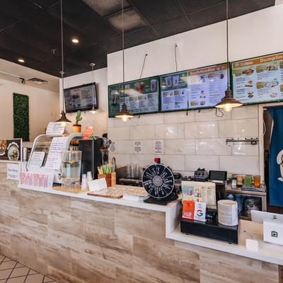Brightly lit restaurant counter with menus displayed above, various items on the counter.