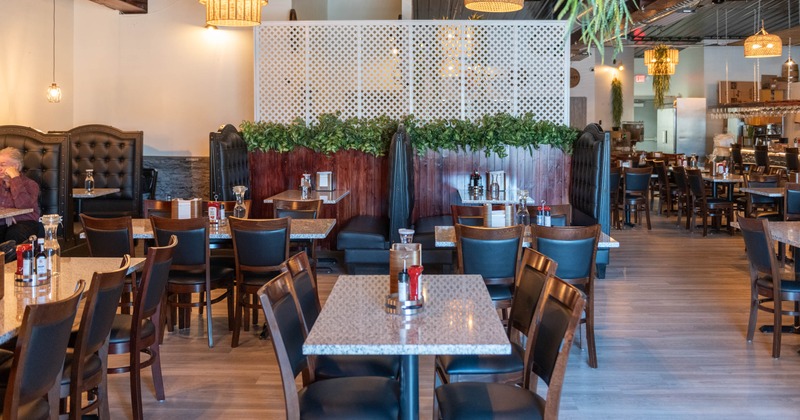 Restaurant interior with wooden tables and chairs, dark leather booths, and rustic wall decorations
