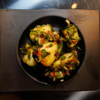 Cucumber salad topped with scallions and fried shallots.