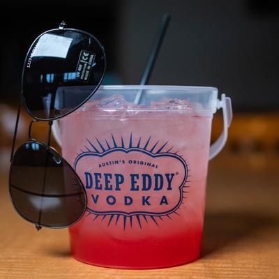 A refreshing red drink with sunglasses attached to the cup.