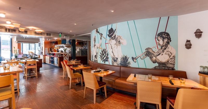 Interior, lined up dining tables and seating, a large mural on the wall