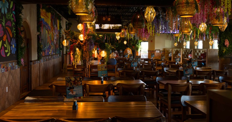 Colorful dining room with hanging flowers, warm lights, and wooden tables