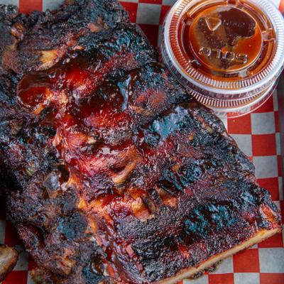 Full rack of baby back ribs served with sauce on the side.