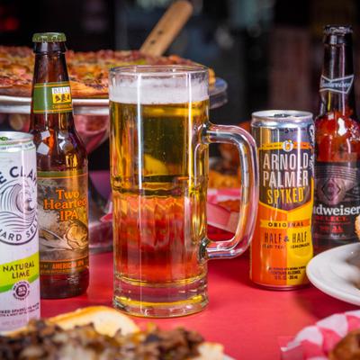 Beer served in a mug, alongside caned and botteled beverages.