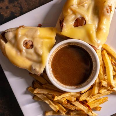 French Dip sandwich, with roast beef, onions, Swiss cheese, and au jus dip.