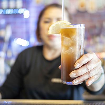 A glass of southern island ice tea in a bartender's hand.
