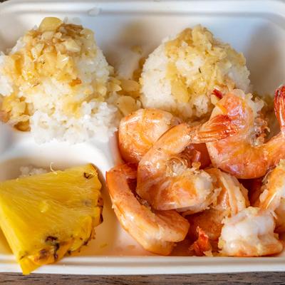 Original shrimp served with white rice, a sauce, and a pineapple wedge.