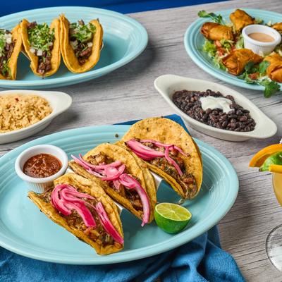 Steak tacos, street tacos, and egg rolls accompanied by salsa, rice and black beans.