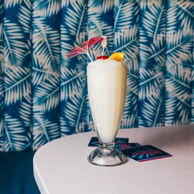Pina Colada on a white table with blue and white leaf patterned seating in the background.