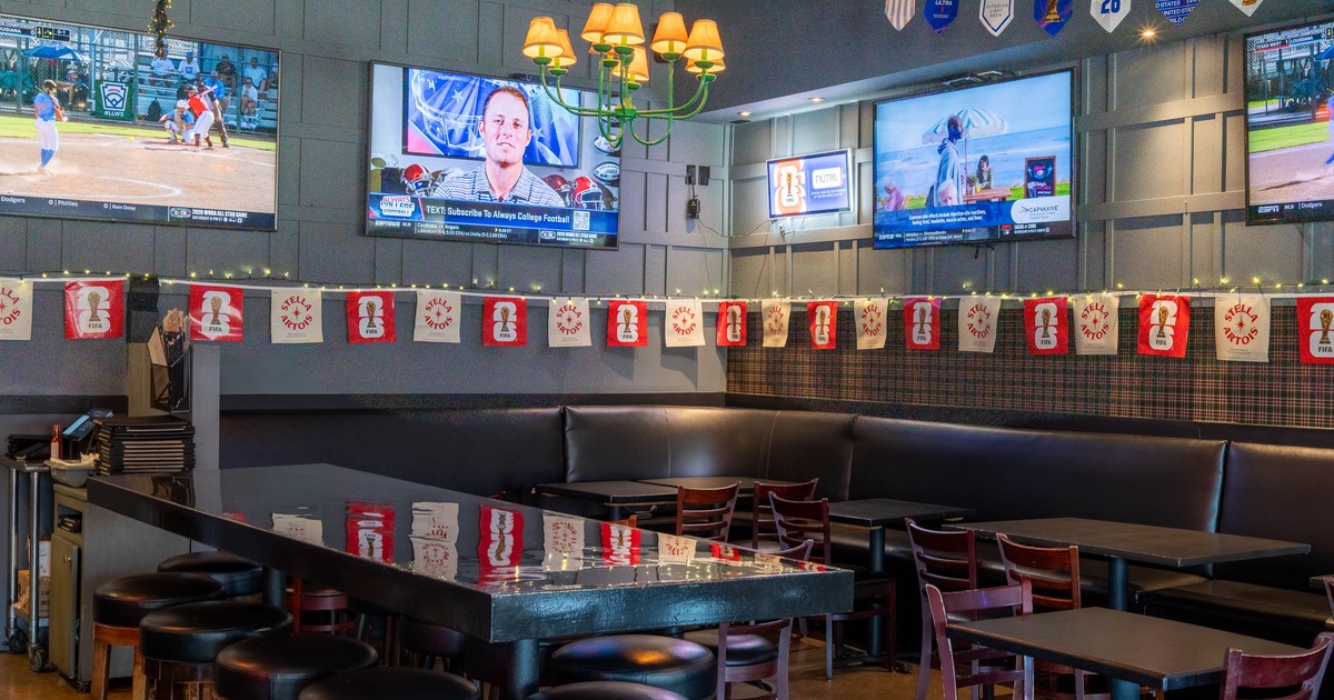 A sports bar interior with three television screens showing various sports