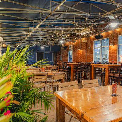 Restaurant's outdoor seating area with tables, chairs and a TV screen.