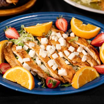 Grilled Chicken Citrus Salad topped with cubed cheese and garnished with fresh fruit.