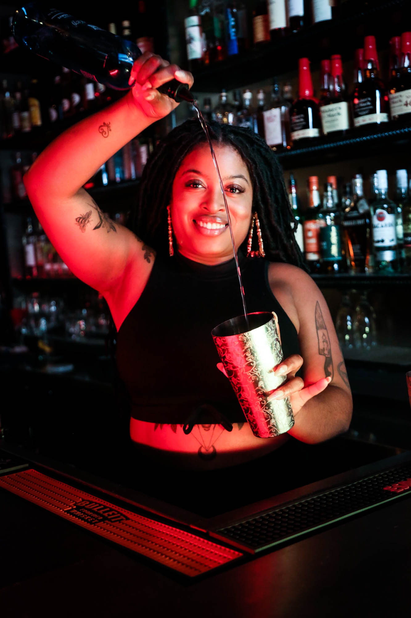 Bar staff smiling, looking at the camera and pouring a drink in shaker photo
