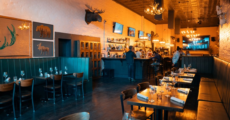Interior of a modern rustic-style restaurant, dining area with set tables and bar